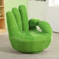 a large green chair sitting on top of a floor next to a book shelf filled with books