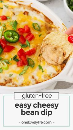 a hand dipping a tortilla chip into a casserole dish with cheese and vegetables