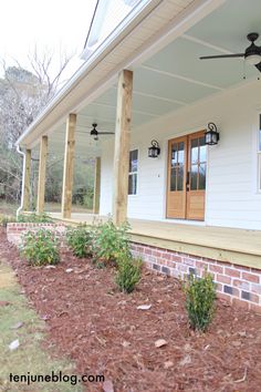 the front porch of a white house with wood trimmings and two ceiling fans