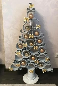 a christmas tree made out of cans with gold ornaments on it's top and bottom