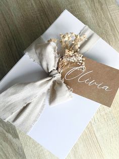 a white card with a brown tag and some dried flowers