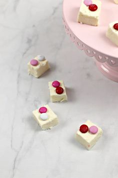 there are many small pieces of cake with candy on the top one is white and pink