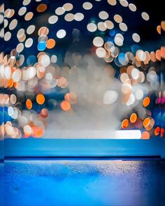 blurry lights are seen in the background behind a blue table top with a glass on it