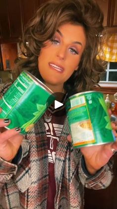 a woman holding two cans of beer in her hands