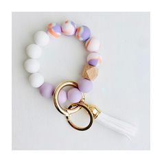 a bracelet with beads and a tassel hanging from it's side on a white surface