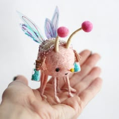 a hand holding a tiny doll in it's palm with some decorations on it