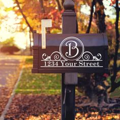 a mailbox with the letter b on it in front of some trees and leaves