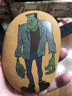 a hand painted rock with an image of a man in a suit and green hands