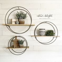 two circular metal shelves with plants and books on them against a white painted wood wall