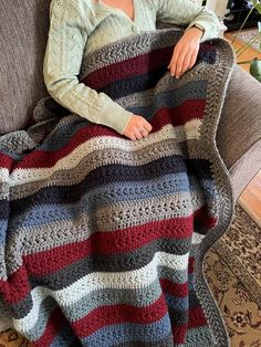 a woman sitting on a couch under a blanket