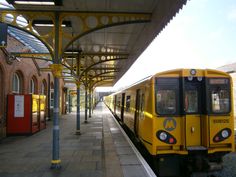 a yellow train pulling into a train station