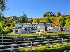 a large white house sitting on top of a lush green hillside