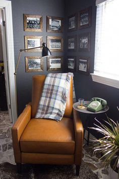 a living room with a chair, lamp and pictures on the wall