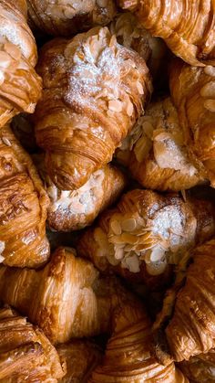 many croissants are piled on top of each other and covered in powdered sugar