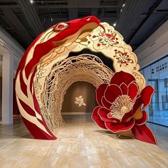 a large red and white sculpture on display in a room with wooden floors, walls and ceilings