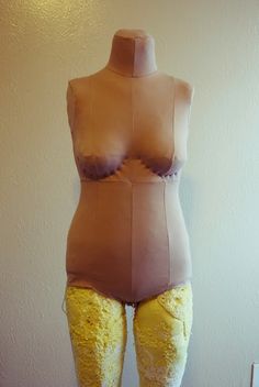 a mannequin with yellow lace on it's legs and butts in front of a white wall