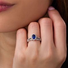 a woman's hand with a ring on her finger and an oval blue stone in the middle