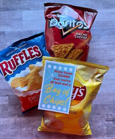 three bags of chips sitting on top of a wooden table