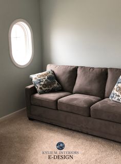 a living room with a brown couch and pillows on the floor next to an airplane window