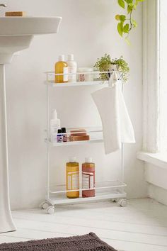 a bathroom with a sink, towel rack and toiletries on it in front of a window