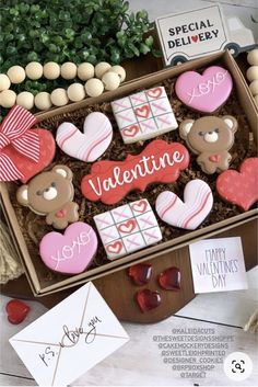 valentine's day decorated cookies in a box with greeting cards and candies on the table