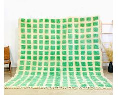 a large green and white blanket sitting on top of a wooden floor next to a chair