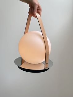 a hand is holding a round bag on a stand