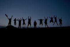 silhouettes of people jumping in the air at dusk