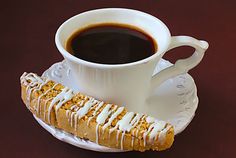 a cup of coffee and some kind of pastry on a saucer next to it