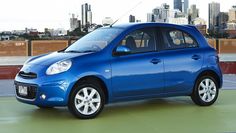 a small blue car parked in front of a city skyline