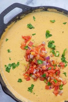 a skillet filled with soup and garnished with cilantro, red onion, and green onions