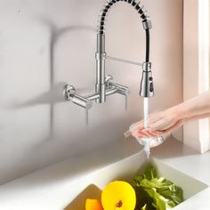 a person washing their hands under a faucet in a sink with fruits and vegetables