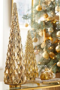 two gold christmas trees sitting on top of a table