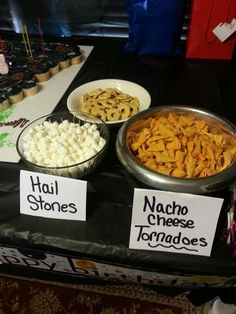 various types of snacks are on display at a vendor's table with name tags