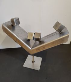 a metal sculpture sitting on top of a white floor next to a wall in a room