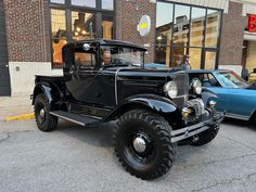 an old black truck parked in front of a building