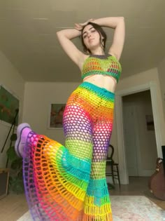 a woman in a rainbow colored outfit posing for the camera with her hands behind her head