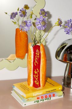 there is a vase with flowers in it on top of some books and a mirror