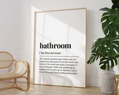 a room with a chair, potted plant and a framed bathroom definition poster on the wall