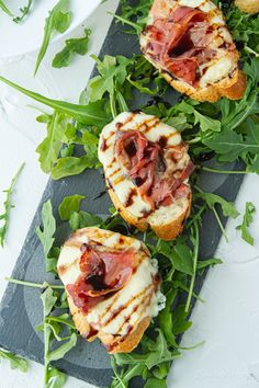 small appetizers with meat, cheese and greens on a black slate platter