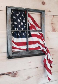 an american flag hanging on the side of a wooden wall next to a small window