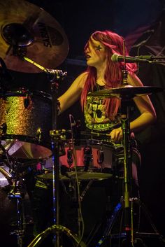 a woman with red hair playing drums on stage