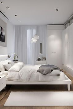 a large white bed sitting in the middle of a bedroom