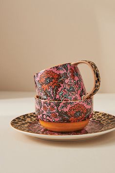 a leopard print cup and saucer sitting on top of a plate with an animal print design