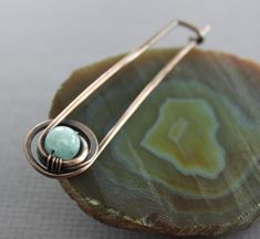 a pair of earrings sitting on top of a piece of wood next to a stone