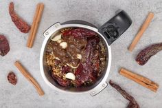 a pot filled with food sitting on top of a counter next to cinnamons and spices