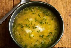 a bowl filled with soup sitting on top of a wooden table next to a spoon