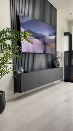 a living room with a large painting on the wall and a potted plant next to it