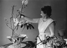 a woman arranging flowers in a vase on a table