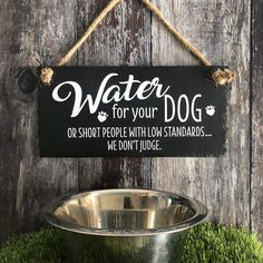 a sign that says water for your dog is hanging on a wooden wall next to a metal bowl